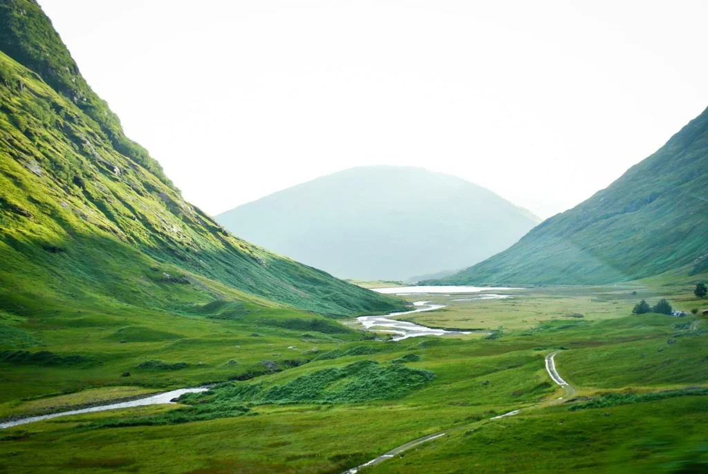 The green valley floor of Glencoe with the River Coe winding towards a loch