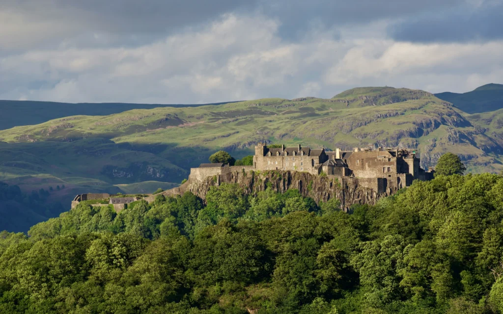 Stirling Castle on its rocky crag above the trees, with hills behind, in central Scotland