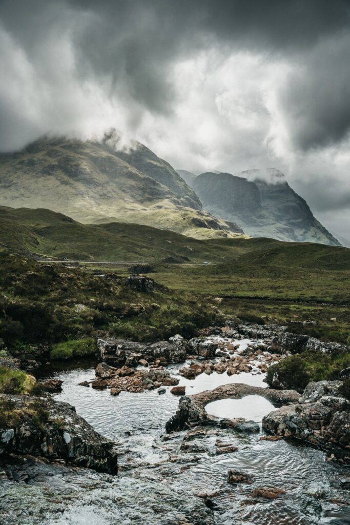 The River Coe running over rocks beneath the Three Sisters on a grey day in Glencoe