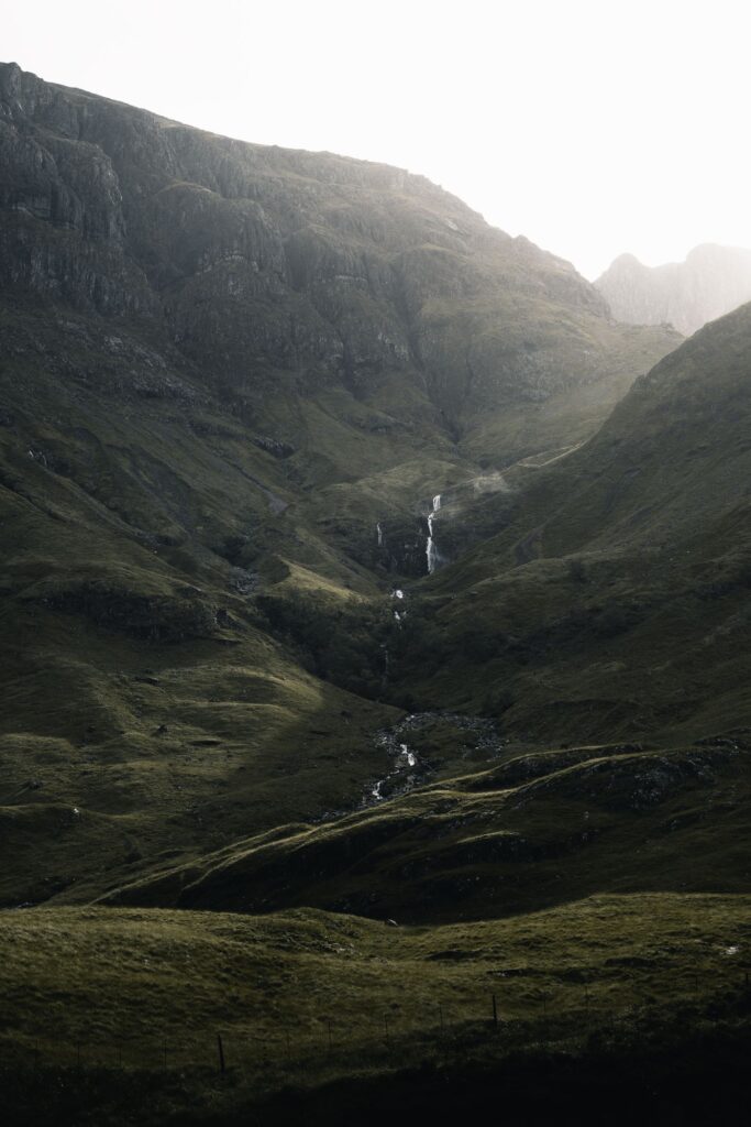 A waterfall tumbling down the green hillside in Glencoe