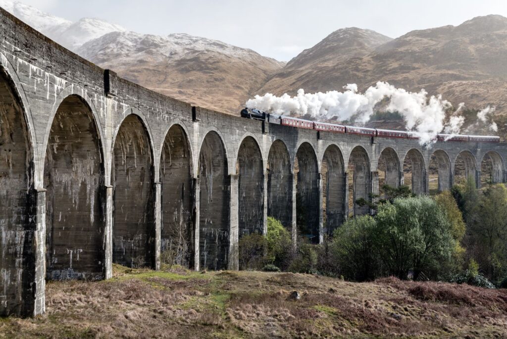 A steam train crossing the concrete arches of the Glenfinnan Viaduct in the Scottish Highlands