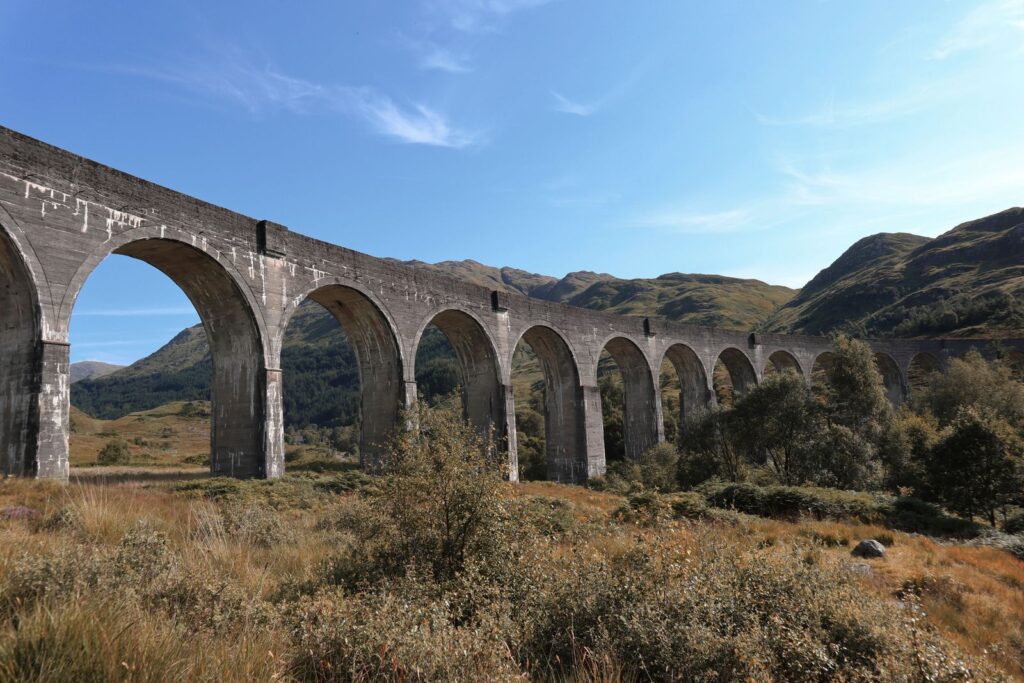 The tall concrete arches of the Glenfinnan Viaduct seen from the path below