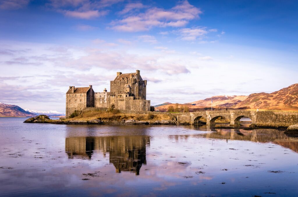 Eilean Donan Castle and its stone bridge reflected in Loch Duich, on the road to the Isle of Skye
